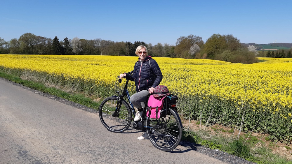 Anja Dieninghoff mit dem Fahrrad vor einem Rapsfeld