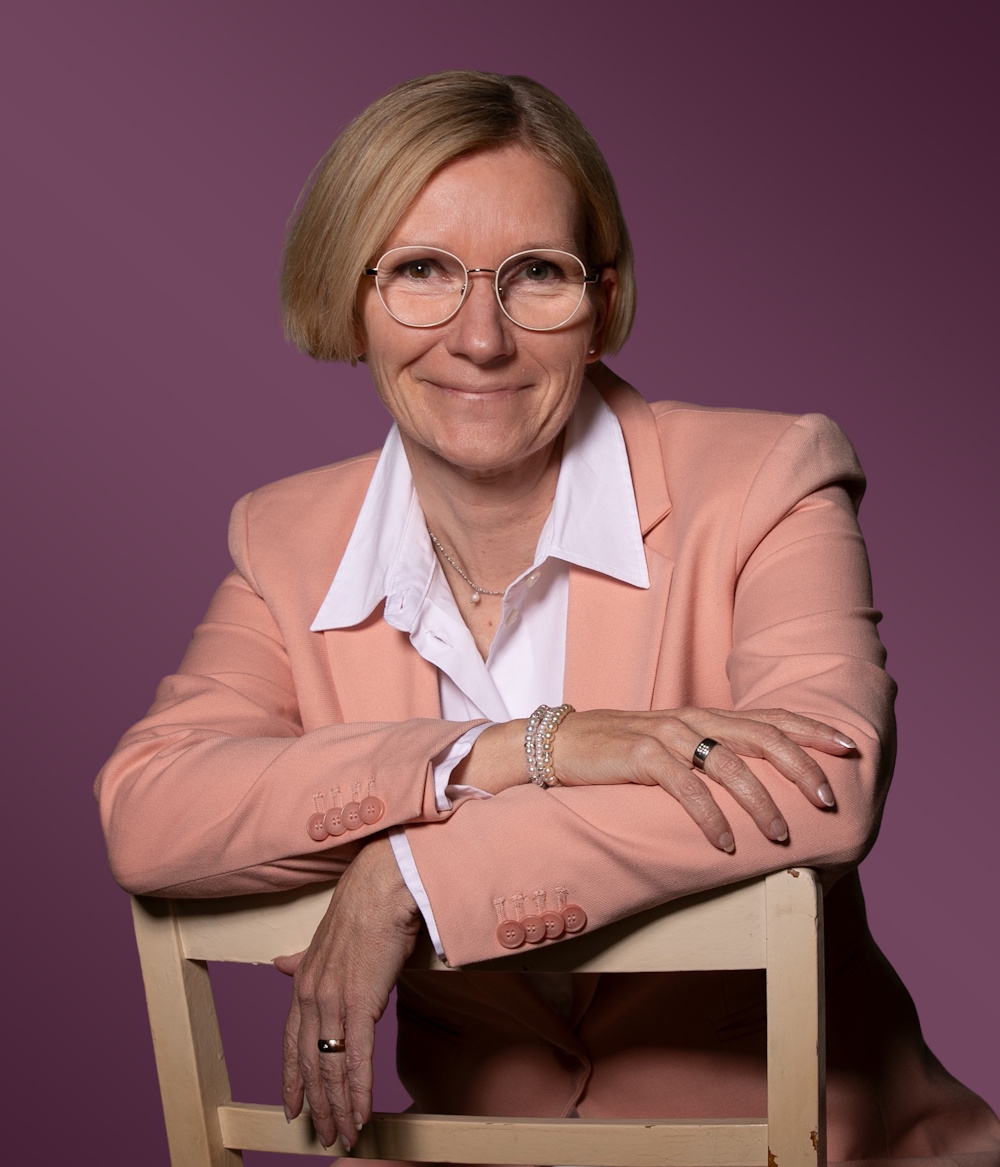 Anja Dieninghoff sitzend im Business-Outfix auf einem Stuhl